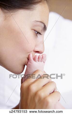 Stock Image - Woman kissing her baby's feet. Fotosearch