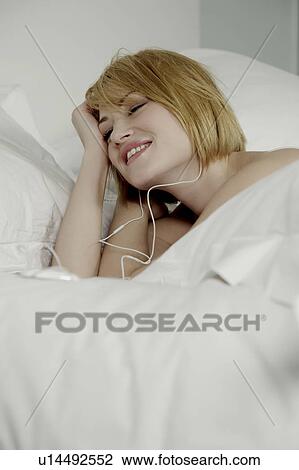 Woman laying in bed wearing earphones. View Large Photo Image Stock Image - Woman laying in bed wearing earphones.. Fotosearch