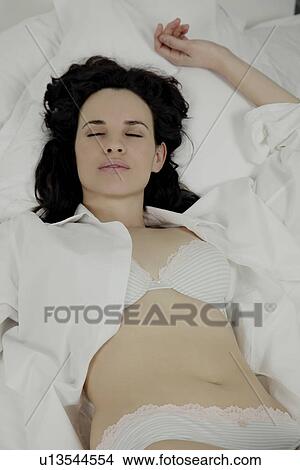 Woman laying on bed, scantily dressed. View Large Photo Image Picture - Woman laying on bed, scantily dressed.. Fotosearch
