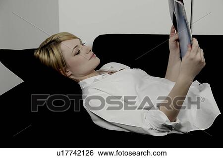 Woman laying on sofa reading magazine. View Large Photo Image Stock Photograph - Woman laying on sofa reading magazine.. Fotosearch