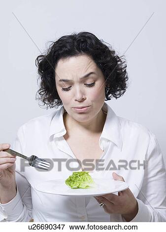 Stock Photo - woman looking at a leaf of salad. Fotosearch