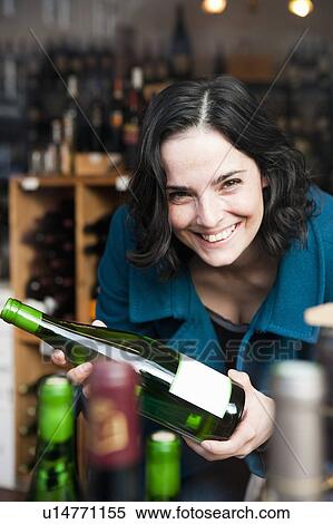 Stock Photography - Woman Looking at Wine Bottle. Fotosearch