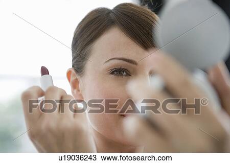 Stock Image - Woman looking in a cosmetic mirror.. Fotosearch
