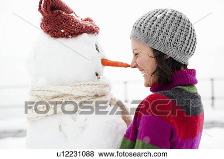 Stock Photo - woman nose to nose with snowman. Fotosearch