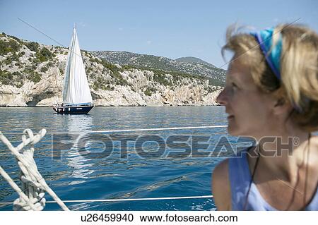 Woman on boat, with coastline visible View Large Photo Image Stock Image - Woman on boat, with coastline visible. Fotosearch