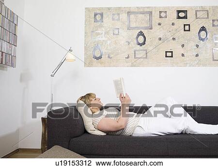Stock Image - Woman on couch, reading.. Fotosearch