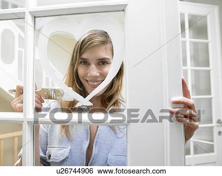 Stock Photograph - Woman painting a heart on the window. Fotosearch