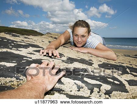 Woman Reaching across rocks to man View Large Photo Image Stock Image - Woman Reaching across rocks to man. Fotosearch