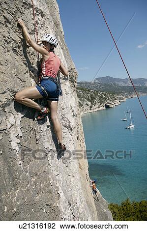 Woman rock climbing, bay in background View Large Photo Image Stock Image - Woman rock climbing, bay in background. Fotosearch