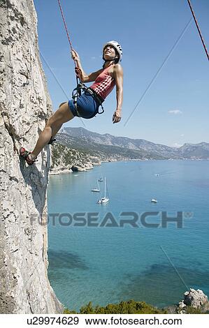 Woman rock climbing, bay in background View Large Photo Image Stock Photo - Woman rock climbing, bay in background. Fotosearch