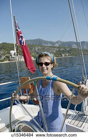 Woman sailing, taking the wheel View Large Photo Image Picture - Woman sailing, taking the wheel. Fotosearch