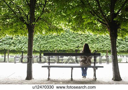 Woman sitting on a public bench View Large Photo Image Stock Image - Woman sitting on a public bench. Fotosearch