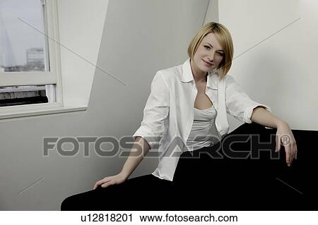 Woman sitting on the edge of a sofa. View Large Photo Image Stock Image - Woman sitting on the edge of a sofa.. Fotosearch