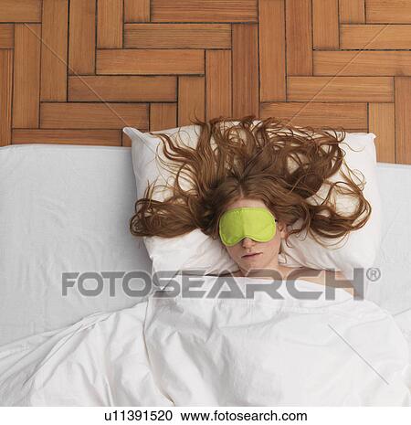 Stock Image - Woman sleeping, wearing eye-mask. Fotosearch