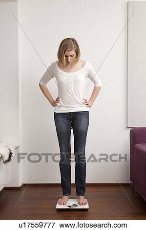 Woman standing on scale View Large Photo Image Stock Photo - Woman standing on scale. Fotosearch