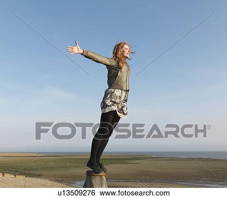 Stock Photograph - Woman standing on wooden post. Fotosearch