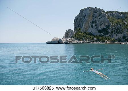 Woman Swimming in blue, rocky bay View Large Photo Image Stock Photography - Woman Swimming in blue, rocky bay. Fotosearch