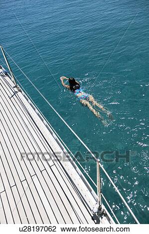 Woman Swimming in next to boat View Large Photo Image Stock Image - Woman Swimming in next to boat. Fotosearch