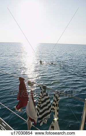 Woman swimming while clothes dry on boat View Large Photo Image Picture - Woman swimming while clothes dry on boat. Fotosearch
