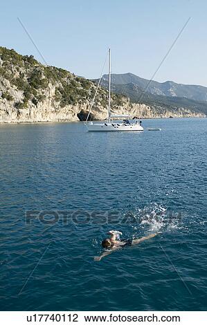 Woman swimming with boat in background View Large Photo Image Stock Image - Woman swimming with boat in background. Fotosearch