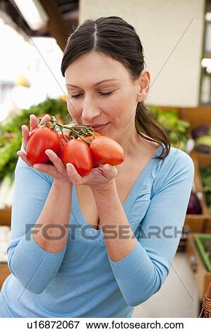 Woman taking smell at fresh tomatoes View Large Photo Image Stock Photo - Woman taking smell at fresh tomatoes. Fotosearch