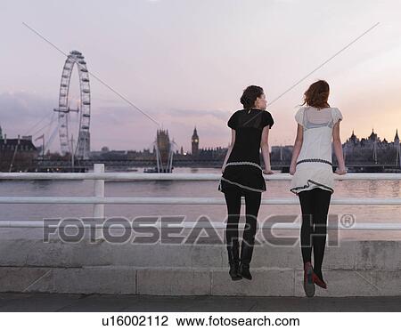 Stock Image - Women drawing on balustrade at sunset. Fotosearch