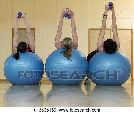 Stock Photo - women exercising with weights at gym. Fotosearch
