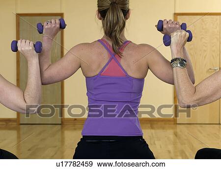 Stock Photo - women exercising with weights at gym. Fotosearch