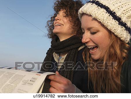 Women holding newspaper, laughing View Large Photo Image Stock Image - Women holding newspaper, laughing. Fotosearch