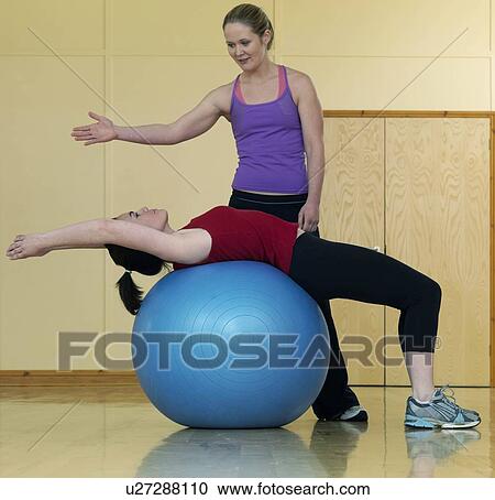 Stock Image - women relaxing at gym with exercise ball. Fotosearch