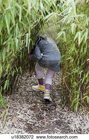 Stock Image - young girl hiding behind plants. Fotosearch