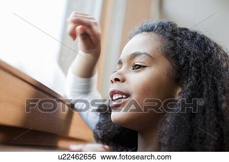 Stock Photograph - young girl looking out a window. Fotosearch