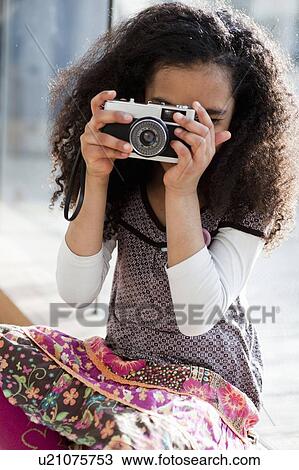 Stock Image - young girl taking picture with camera. Fotosearch