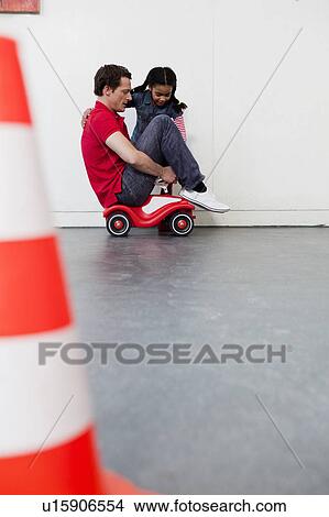 young girl teaching man to ride toy car View Large Photo Image Picture - young girl teaching man to ride toy car. Fotosearch