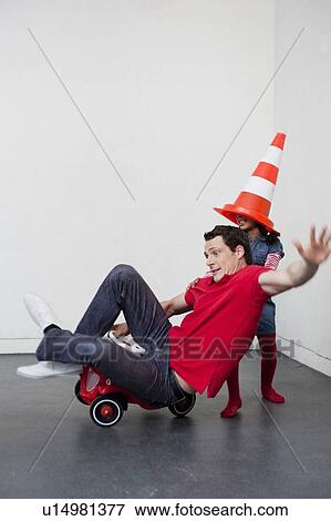 young girl teaching man to ride toy car View Large Photo Image Stock Photo - young girl teaching man to ride toy car. Fotosearch