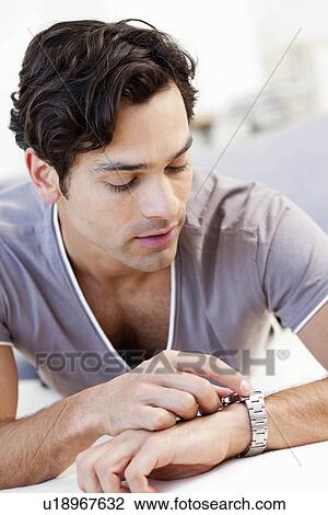 Stock Image - young man checking the time. Fotosearch
