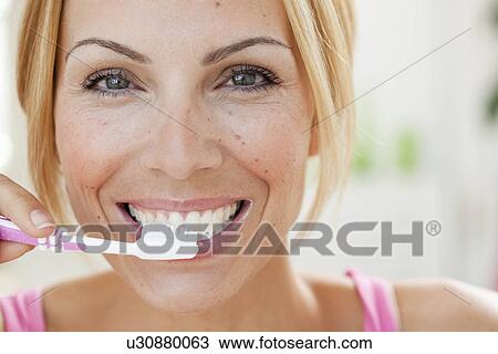 Stock Image - young woman brushing teeth. Fotosearch