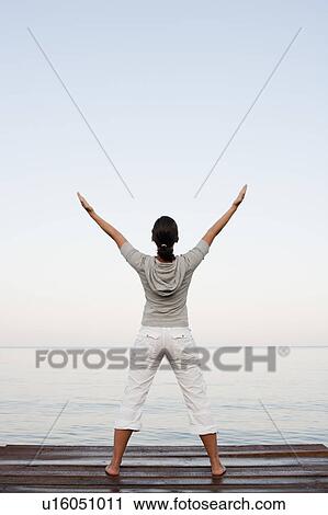 Stock Image - Young Woman Doing Yoga At Jetty. Fotosearch