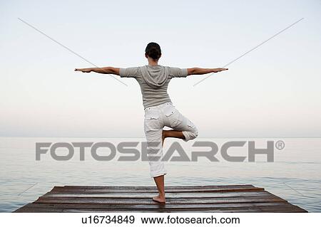 Stock Photo - Young Woman Doing Yoga At Jetty. Fotosearch
