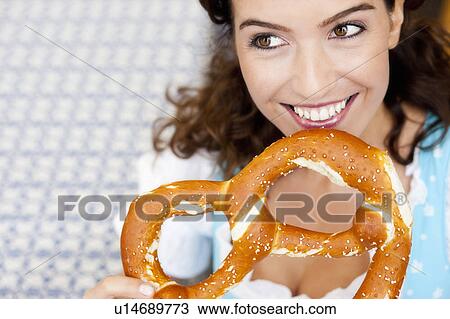 Stock Image - Young Woman Eating Huge Pretzel. Fotosearch