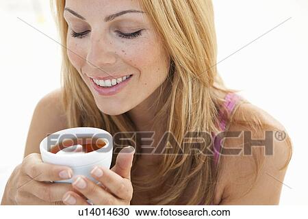 Stock Image - young woman enjoying cup of tea. Fotosearch