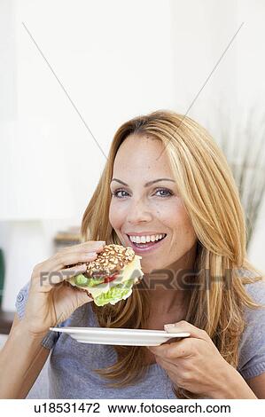 Stock Image - young woman having sandwich. Fotosearch