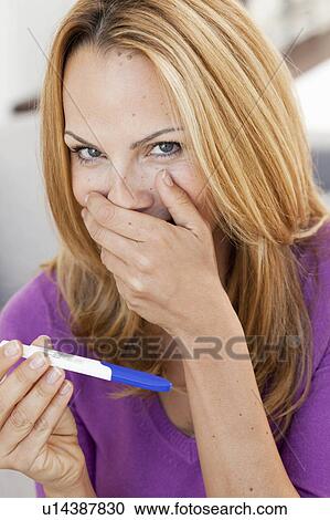 Stock Image - young woman holding pregnancy test. Fotosearch