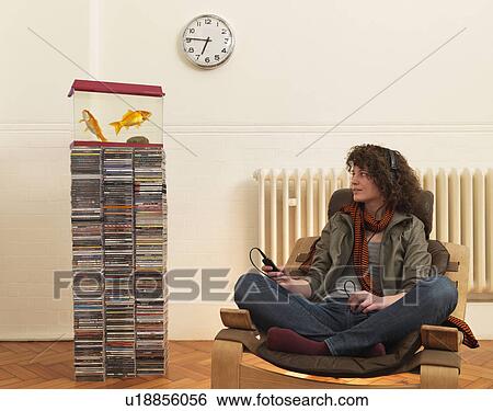 Young woman in chair listening to music View Large Photo Image Stock Photograph - Young woman in chair listening to music. Fotosearch