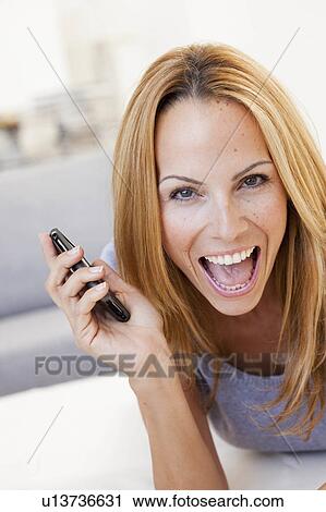 Stock Image - young woman screaming into cell phone. Fotosearch
