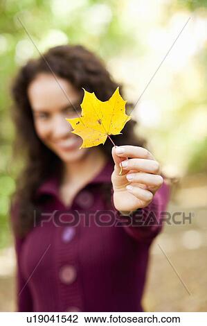 Stock Image - young woman shows leaf. Fotosearch