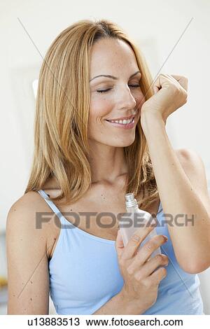 Stock Image - young woman smelling perfume. Fotosearch