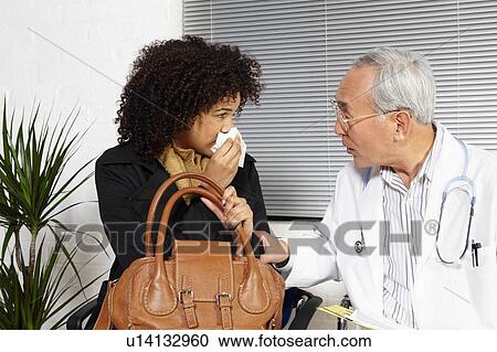 Stock Image - Young woman talking to doctor. Fotosearch