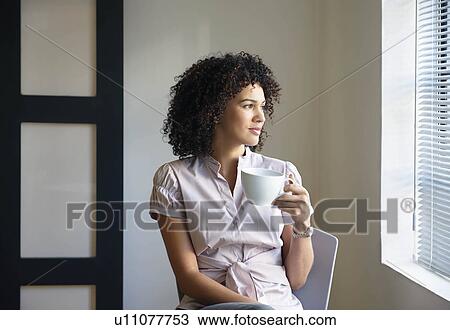 Stock Image - Young woman with cup, thinking. Fotosearch