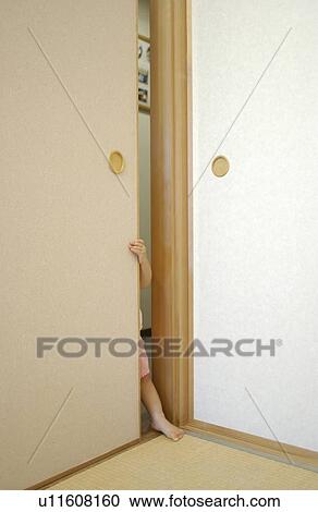 Stock Image - Arm and leg of baby girl peeking over fusuma . Fotosearch